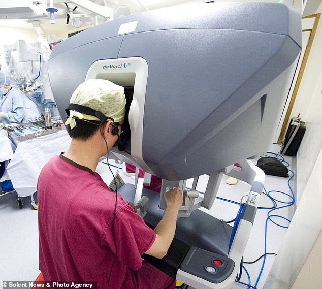 Doctors performing surgery with the robot operate the arms from behind a console.