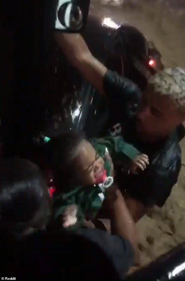 Marcos de Souza hands over one of the two one-year-old twin sisters that he rescued with his mother on Wednesday night after being trapped in his family's car on a flooded street in Rio de Janeiro.