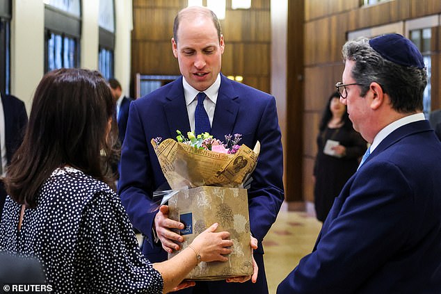 Prince William receives a bouquet of flowers for his wife Catherine, Princess of Wales, during their visit to the Western Marble Arch Synagogue, London