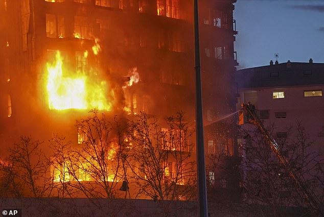 Firefighters work to extinguish the flames as they continue to raze the residential block.