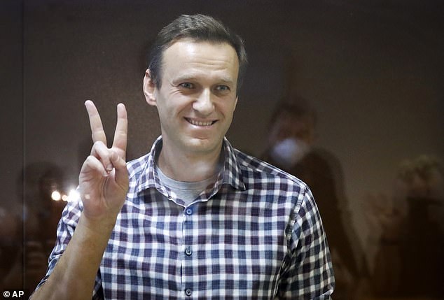 FILE - Russian opposition leader Alexei Navalny gestures while standing in a cage at the Babuskinsky District Court in Moscow, Russia, Saturday, Feb. 20, 2021.