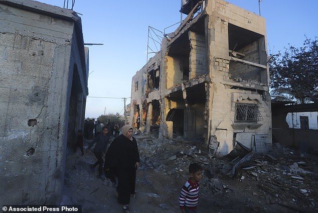 Palestinians walk past a residential building destroyed in an Israeli strike in Rafah, Gaza Strip, Sunday, February 11, 2024.