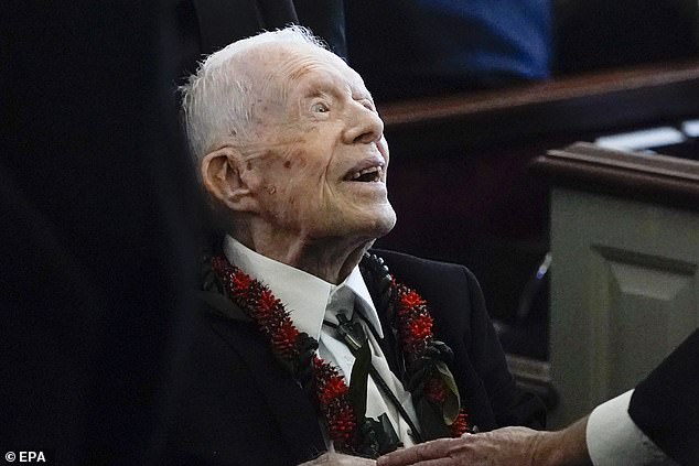 Jimmy Carter at his wife Rosalynn's funeral, wearing a red necklace in her honor. The November service was his only public appearance since he entered hospice care.
