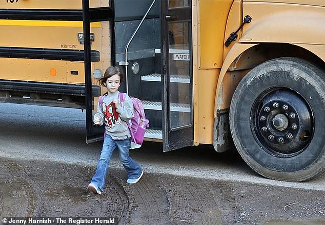 Five-year-old Kolbie Hale, carrying a backpack, is seen getting off the school bus after a grueling ride.