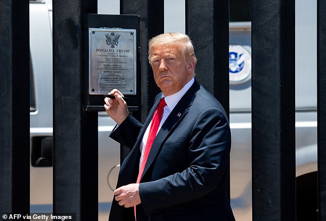 President Donald Trump looks on before signing a plaque while participating in a ceremony commemorating the 200th mile of the border wall.