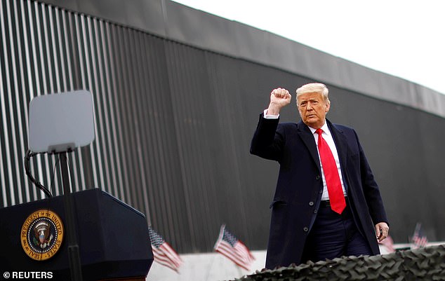 US President Donald Trump raises his fist while visiting the US-Mexico border wall.