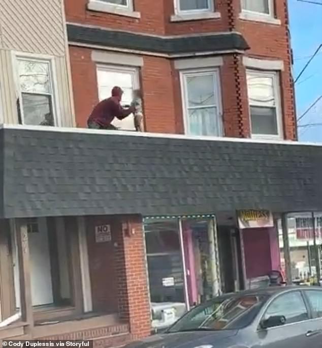 The man is seen grabbing the boy who was caught walking alone on a roof Tuesday morning on South Main Street in Woonsocket, Rhode Island.