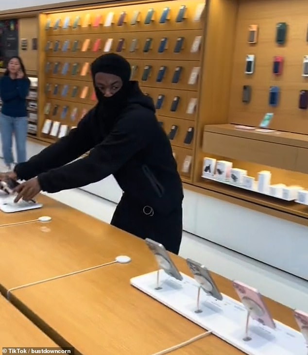 This is the crazy moment a daring thief casually rips an entire display of iPhones off the shelves of an Oakland Apple store amid Newsom's latest efforts to crack down on crime in the area.
