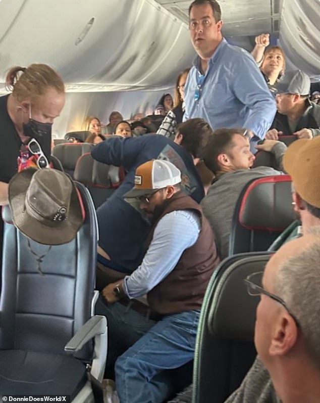 Footage shows five men on American Airlines Flight 1219 restraining an unruly passenger after he tried to open the emergency exit door 30 minutes after the plane departed Albuquerque International Sunport for Chicago.