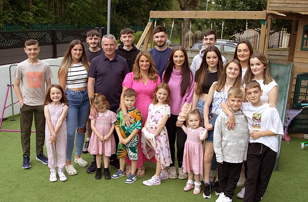 Pictured: Noel and Sue Radford pose with 18 of their 22 children in the garden of their Morecambe home.