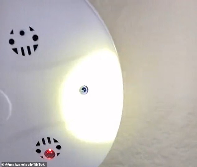 A bright light shining on a smoke detector reveals the telltale glow of a lens placed in a hole.