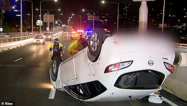 The driver and three passengers inside an allegedly stolen car fled the scene after a two-vehicle crash that caused a white Mazda 3 sedan (pictured) to overturn.