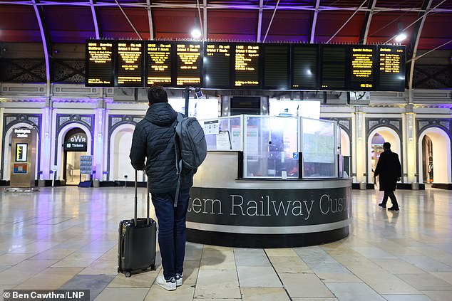 A commuter looks at the departures board at Paddington station in London on another day of rail strikes.