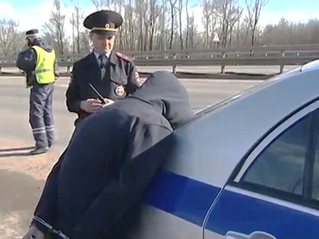 Arrested: One of the young men is ordered to lean face down on a police car after being detained in a 'stolen' vehicle