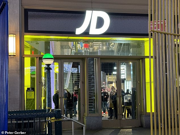 Shoppers stand inside the JD Sports store in Times Square after robbers shot a Brazilian tourist inside the store.