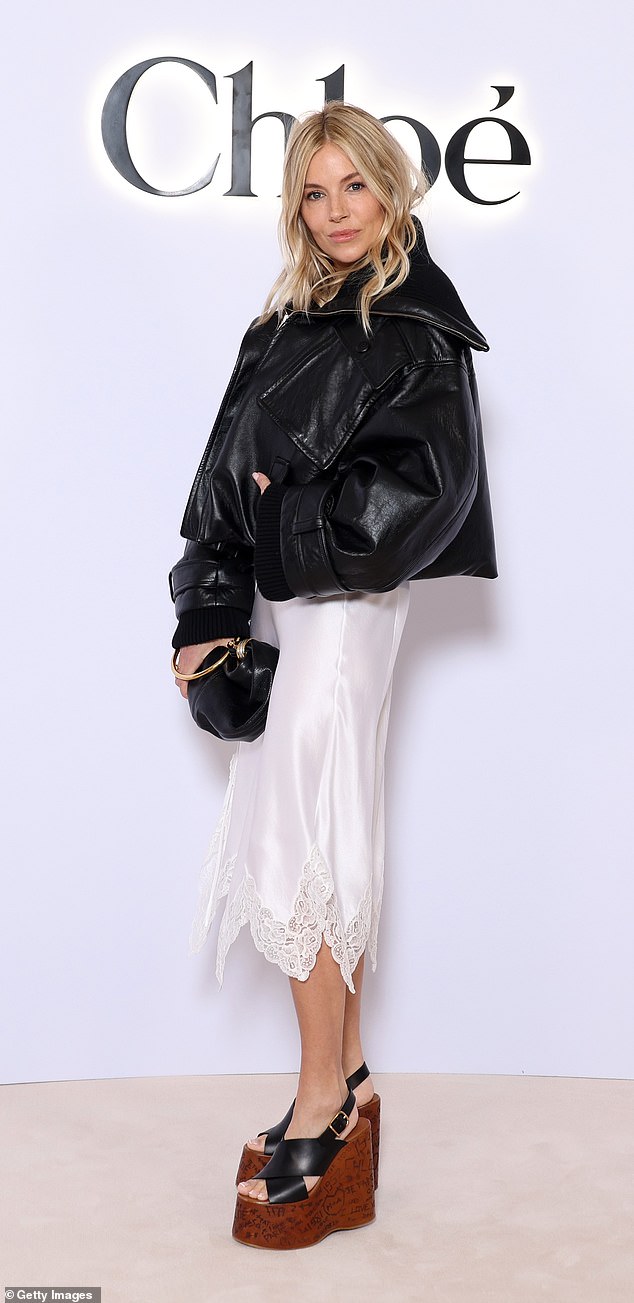 Posing for photos at Chloé's Fall/Winter 2024-2025 collection, she wore a contrasting leather bomber jacket over her elegant lace-trimmed midi dress.