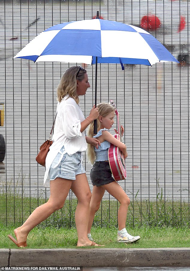 Fans are seen sheltering under umbrellas as they arrive at Sydney Airport to greet Taylor Swift.