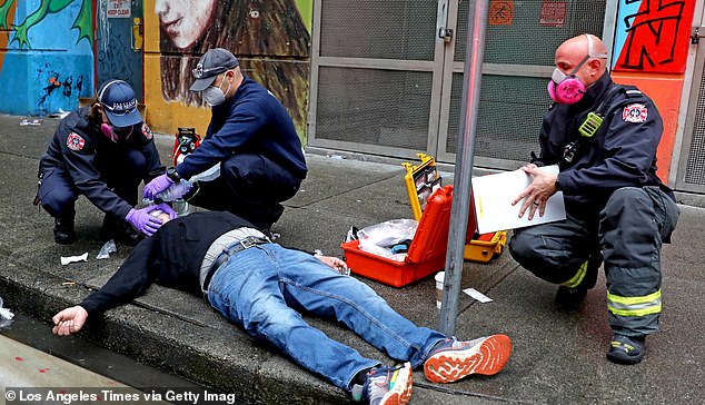 Last year, the province of British Columbia, which includes Vancouver, announced the start of a three-year experiment to decriminalize all hard drugs.  (Pictured: Doctors treat an overdose victim in Vancouver in May 2022)