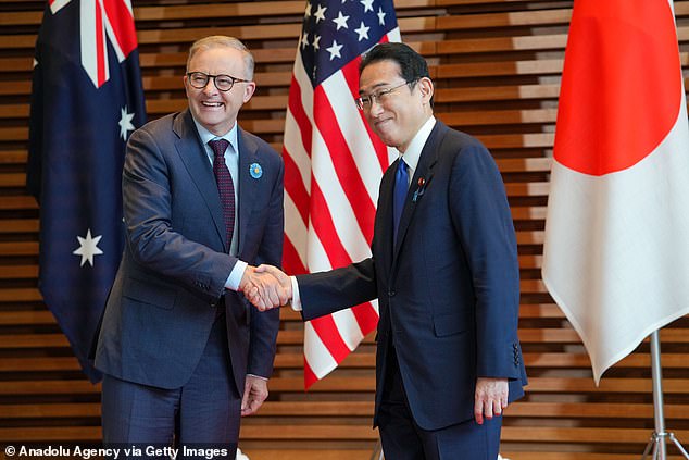New Australian Prime Minister Anthony Albanese (left) wears a bright blue badge to identify him as he shakes hands with Japanese leader Fumio Kishida (right).