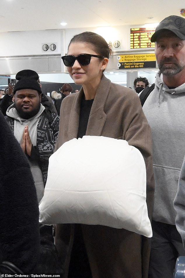 The actress stayed comfortable during her international travels, wearing an oversized camel coat over a black shirt.
