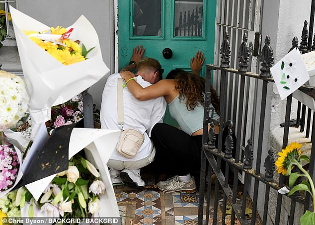 Mourners are seen spending time by the front door of Mr Baird's home, where he and his partner Luke Davies were allegedly murdered on February 19.