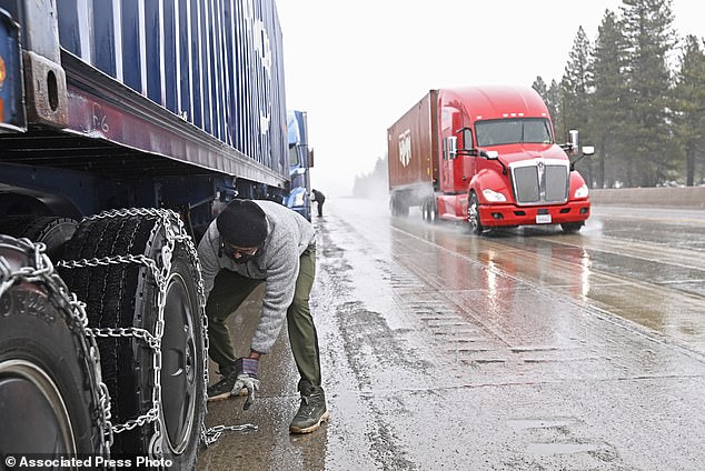Mangal Singh parks his truck along I-80 to put chains on the wheels of his truck in preparation for the snow storm over the Sierra Nevada on Thursday, February 29, 2024 in Truckee, California. A storm in the Pacific with strong winds and heavy snow. It is shaping up to be the strongest of the season, meteorologists say. (AP Photo/Andy Barrón)
