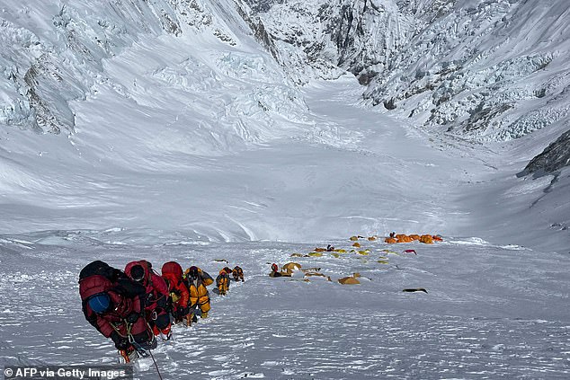 A group of mountaineers climbing a slope lined up during their ascent to the summit of Mount Everest in 2021.