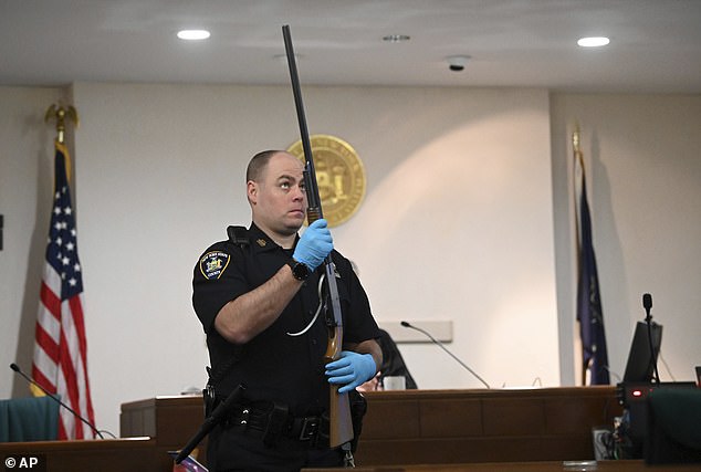 A New York State Court police officer holds Kevin Monahan's shotgun during summaries in Monahan's murder trial.