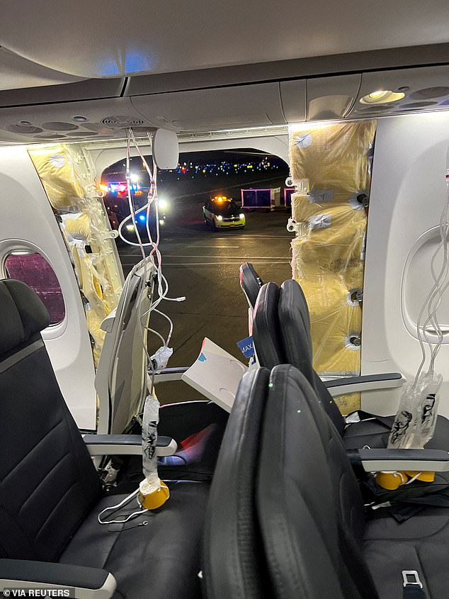 Passengers' oxygen masks hang from the ceiling panels next to a missing window and a portion of a side wall of Alaska Airlines Flight 1282, which was headed to Ontario, California.