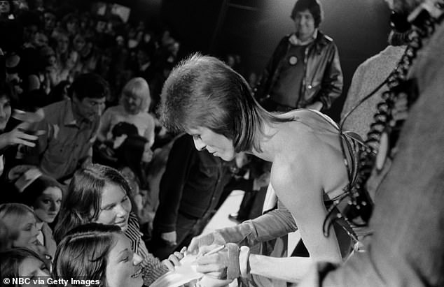 Pictured: David Bowie was seen signing autographs for his fans in 1973 while on stage as Ziggy Stardust.