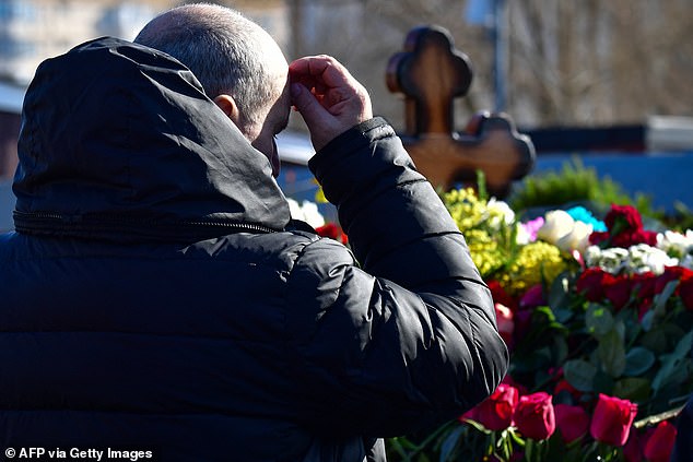 grave after dozens of supporters were detained for flocking to the Putin critic's funeral.  Defiant mourners have braved the fury of the Russian state, which arrested nearly 70 people across Russia for daring to mourn the loss of the opposition figure.