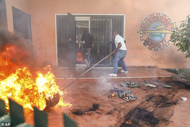 Workers put out a fire at the office of Haiti's power company after it was attacked by protesters.