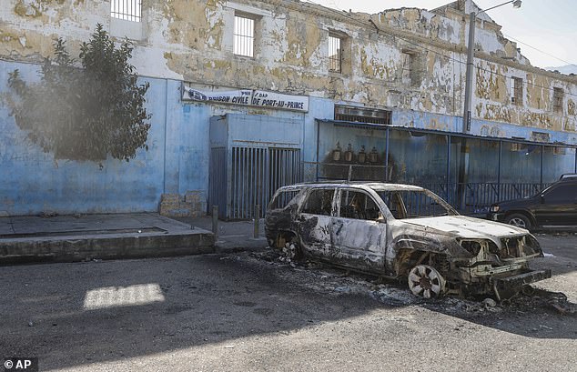 Pictured: A burned car outside the city's National Penitentiary prison, where hundreds of inmates reportedly escaped.