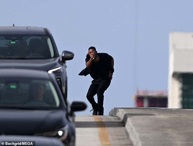 The actor, 55, was seen filming a high-octane chase scene, in which he aimed a prop gun at the side of a road on a bridge.