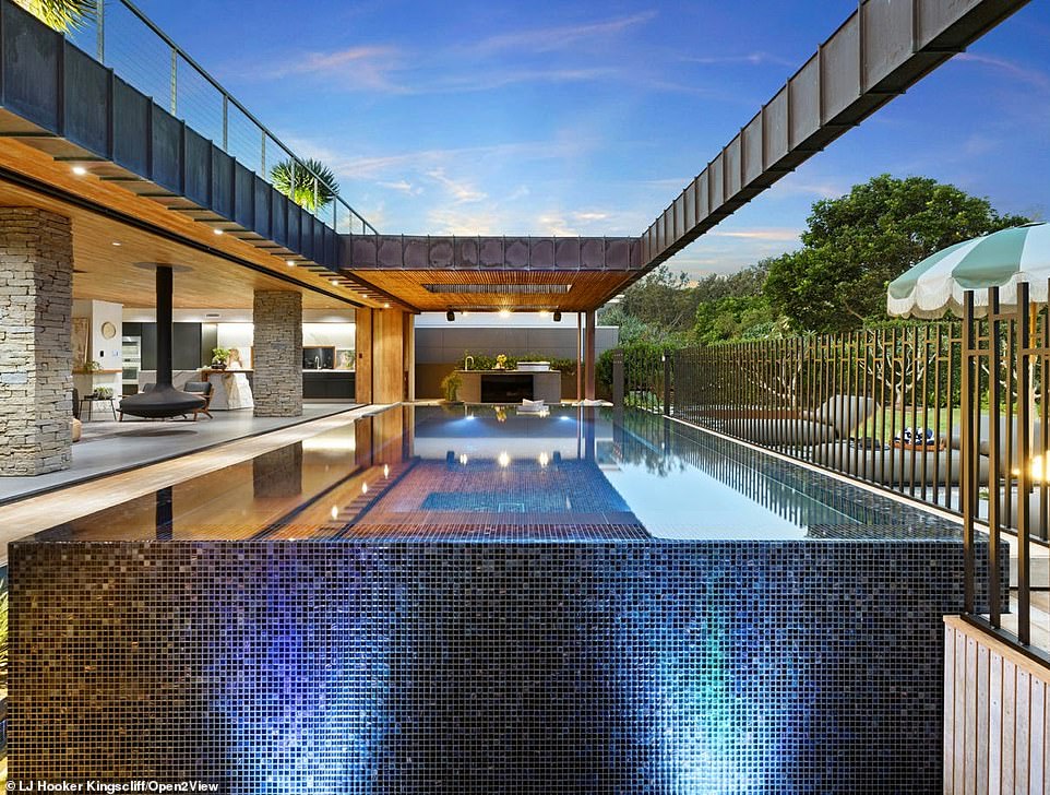 Outside, the covered terrace has an elevated mosaic infinity pool surrounded by a shallow pond and a void below that lets in sunlight.
