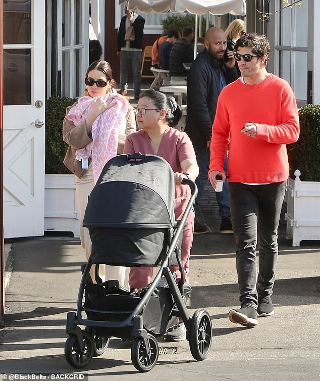 The adorable new parents strolled through an outdoor shopping center together, paying attention to their precious cargo.