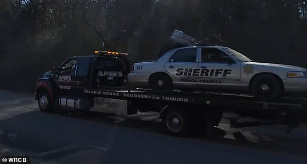 The officer's car is seen being towed after being swept out of the Tennessee River.