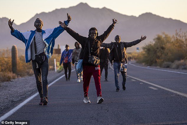 Immigrants from the West African nation of Guinea are seen striking a celebratory pose after crossing the U.S.-Mexico border on December 7, 2023 in Lukeville, Arizona.