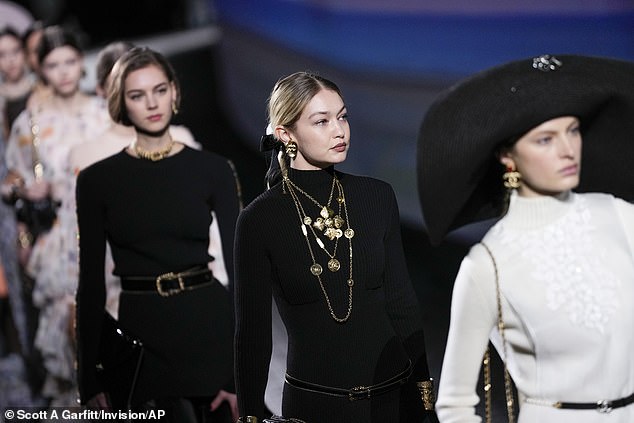 For the Chanel show, Gigi wore a long black knit dress with a sheer skirt that she paired with a series of gold necklaces.