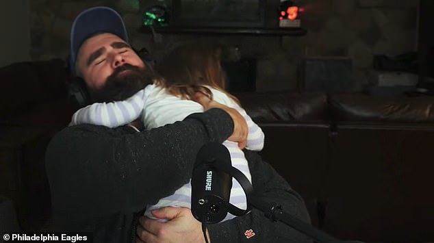 Kelce hugs one of his daughters while recording his hit podcast New Heights with his brother Travis.