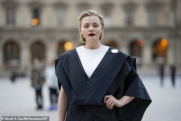 She cut an elegant figure with statement gold earrings and a touch of burgundy lipstick for the Paris Fashion Week show.