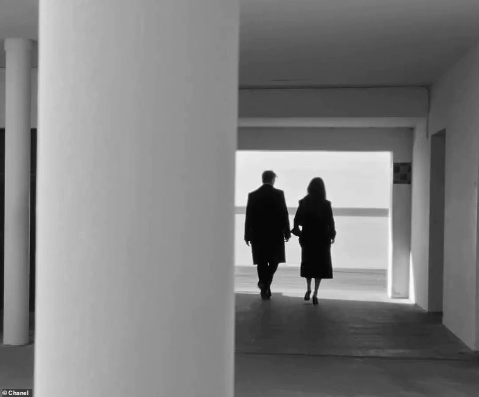 They walk together through a building that leads them to the sandy beach.