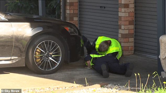 Police are seen inspecting a vehicle at a home meters from the alleged hit-and-run.