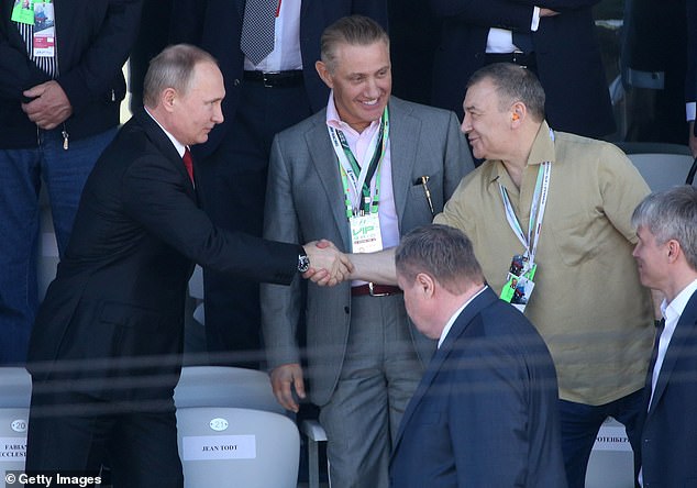 Russian President Vladimir Putin (L) shakes hands with billionaire and businessman Arkady Rotenberg (R), while his brother, Boris Rotenberg (L), looks on