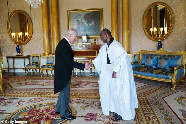 King Charles shakes hands with the Mauritanian ambassador, Samba Mamadou, today at Buckingham Palace