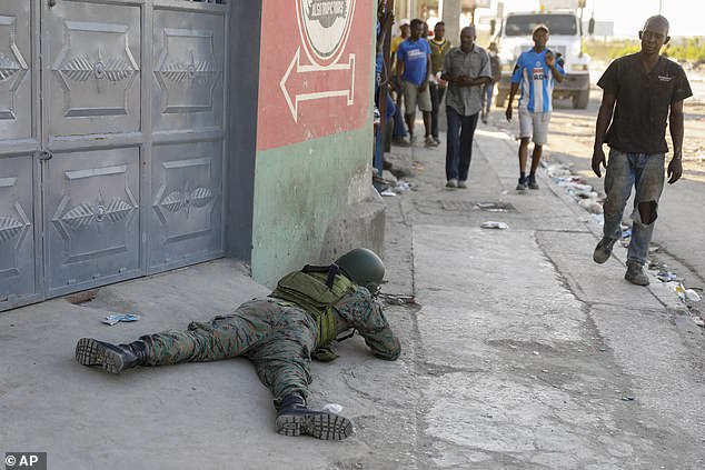 Pedestrians pass by a soldier guarding the area of ​​the attacked international airport in Port-au-Prince
