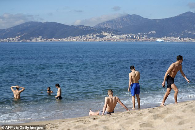 Men bathe in the sea at 14°C during a warm weekend, with the Sanguinaires Islands in the background, on the French Mediterranean island of Corsica, in Porticcio, on February 18, 2024.