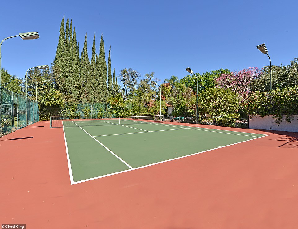 A tennis court is surrounded by lush greenery. The home is listed by Hilton & Hyland/Forbes Global Properties. Neil McDermott and Beate Kessler-McDermott of Hilton & Hyland/Forbes Global Properties maintain the listing