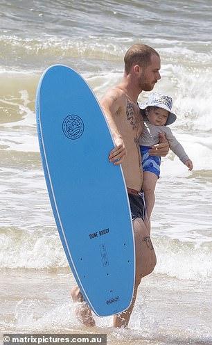 Sam helped carry the couple's big blue surfboard while Jordie and his son rode the waves.