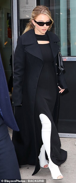 Action star Madame Web, 26, wore white high-heeled legging-style boots with a long black dress under a matching coat.
